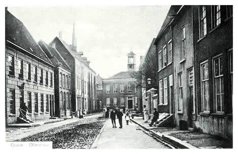 De Oliestraat wordt aan de zuidzijde gemarkeerd door de neo-classicistische frontgevel van het St. Catharinagasthuis uit 1836. Deze instelling werd in 1290 gesticht door de heer Jan van Cuijk. Ondanks belegeringen en branden is het archief bijna ongerept tot ons gekomen. De marechausseekazerne met daarachter de Wijnberg, een blindeninrichting voor meisjes, zien we links, en uiterst rechts is de drukkerij en uitgeverij van de firma van Dieren gevestigd, die tevens de Graafsche Courant uitgaf. Tot vandaag wordt dit alles voortgezet door de firma Verhaak.