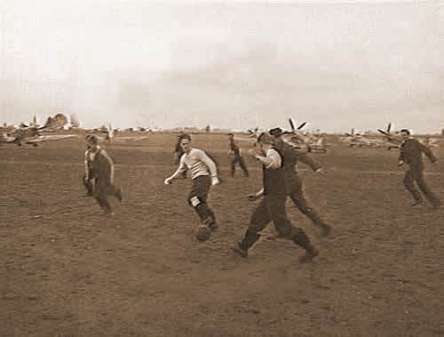 Australische en Engelse piloten en grondpersoneel van 130 (Punjab) Squadron spelen een ontspannend partijtje voetbal op de voorgrond van een indruk- wekkend rijtje Spitfires. (Foto is genomen op 23 oktober 1944).