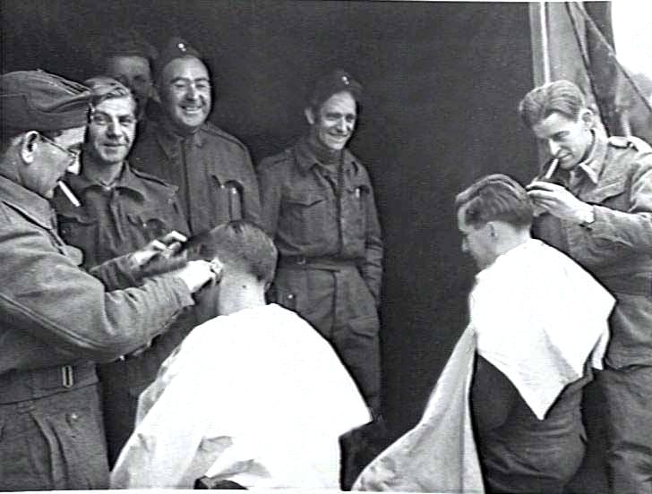 "Get yer 'air cut!!", zelfs tijdens de traumatische dagen op B.82 gaat het leven gewoon door als grondpersoneel - tussen de starts en landingen van de squadrons door - in de rij staat om geknipt te worden. (Foto gemaakt op 23 oktober 1944)