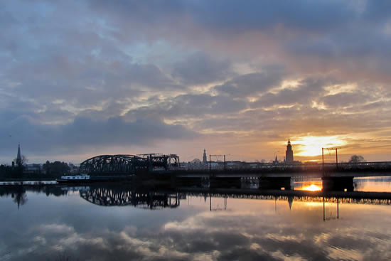Hier zien we de prachtige zonsopkomst bij rivier de IJssel, met een mooie weer- spiegeling van de skyline van Zutphen in het bewegingsloze IJsselwater. (foto gemaakt door Carolien Bentink op 26 januari 2011).